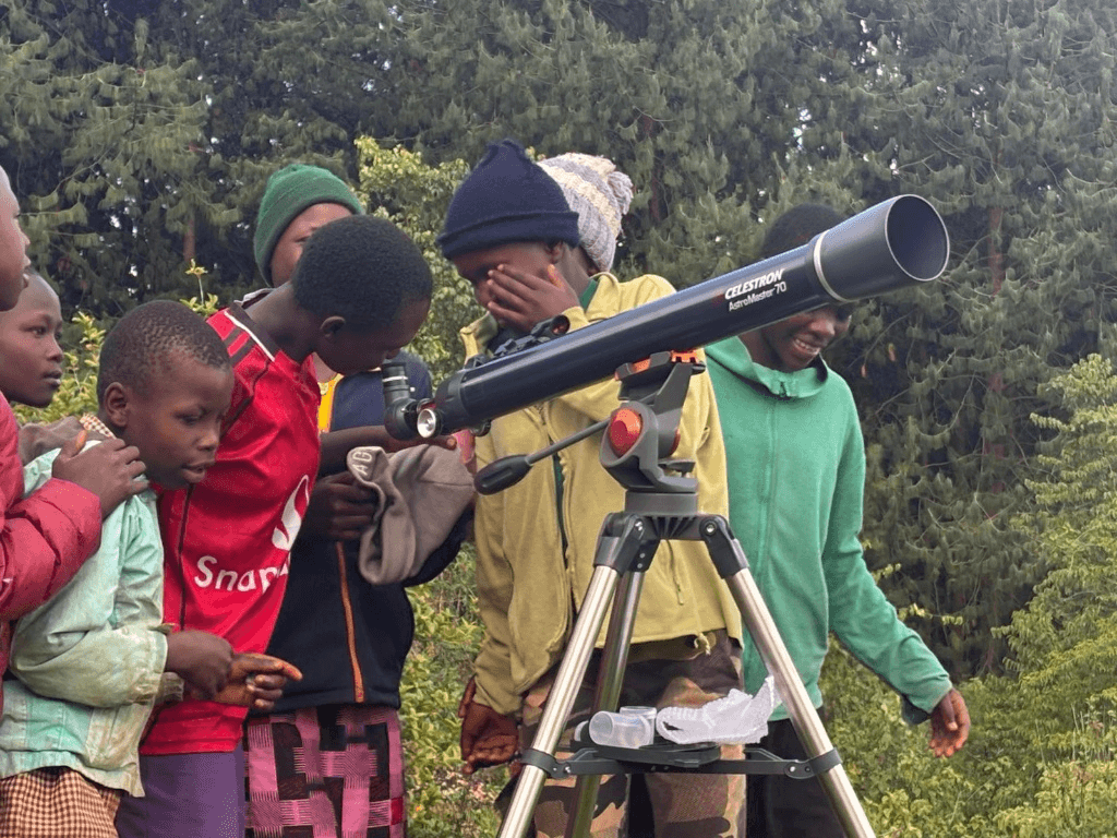 Children enthusiastically looking through a Celestron telescope during a ForbSpace community outreach and data mapping exercise in the Mt. Elgon region.